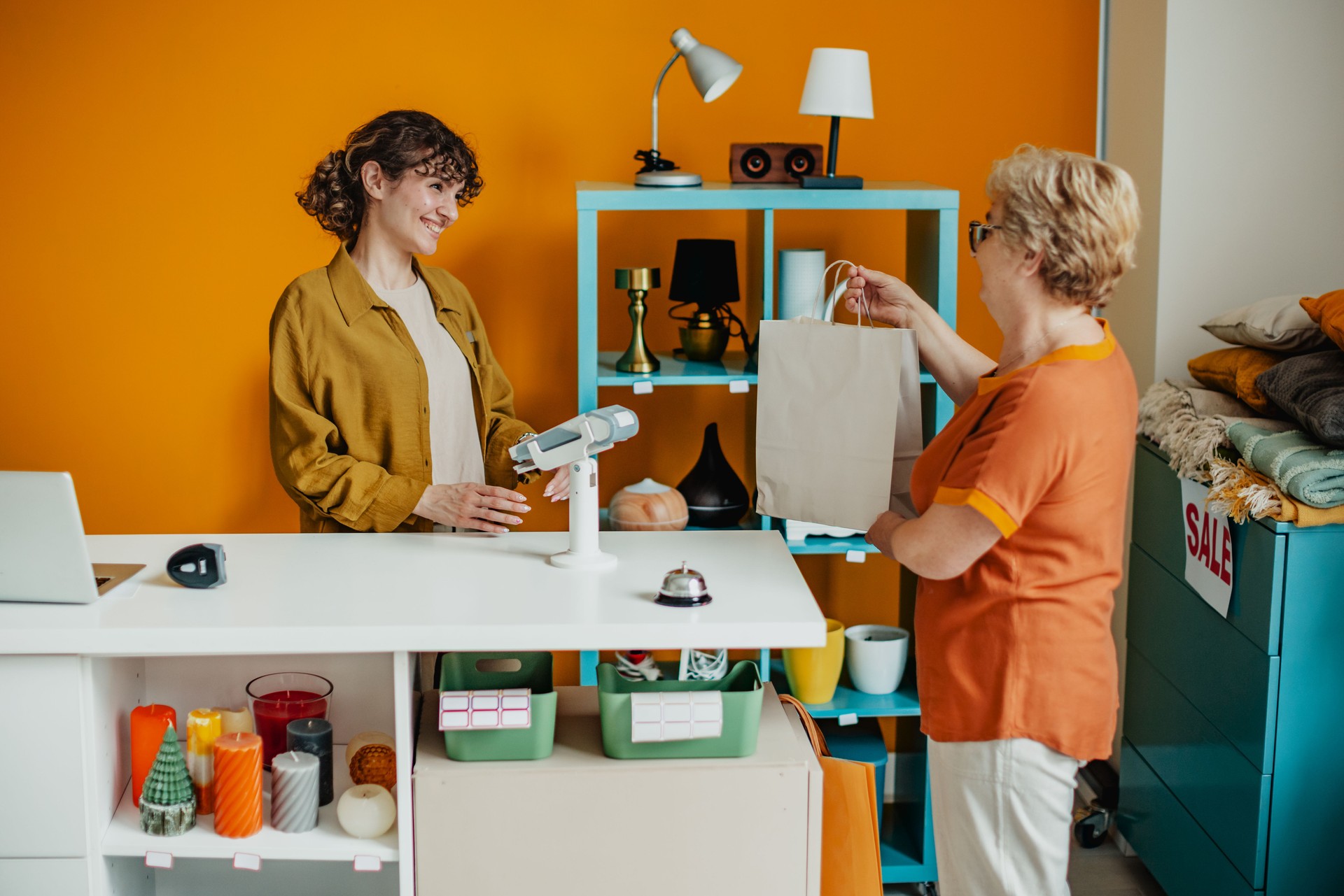 Young woman assists customer at vibrant gift shop while selling unique items