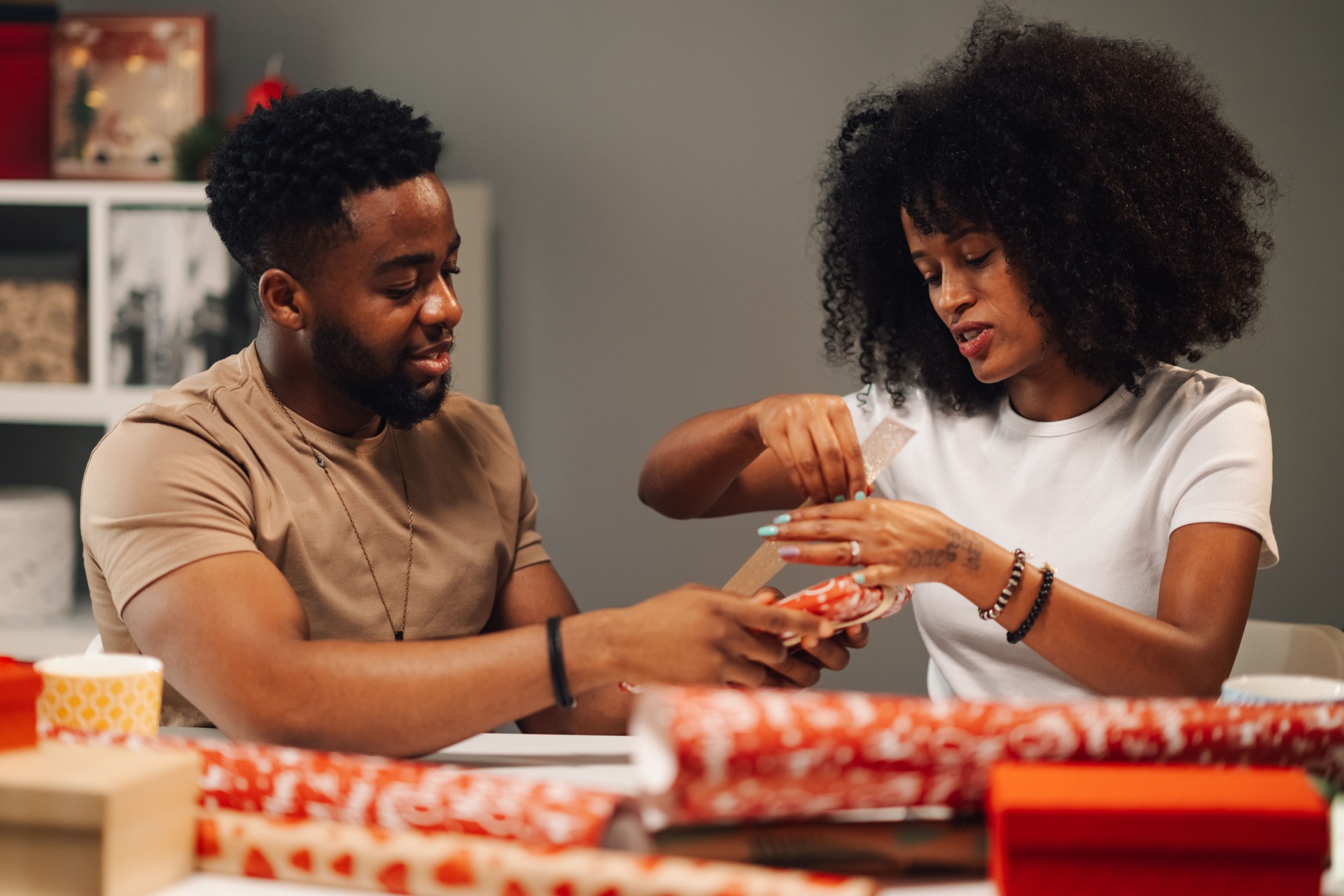 African american couple collaborating on holiday gift wrapping, sharing joy.