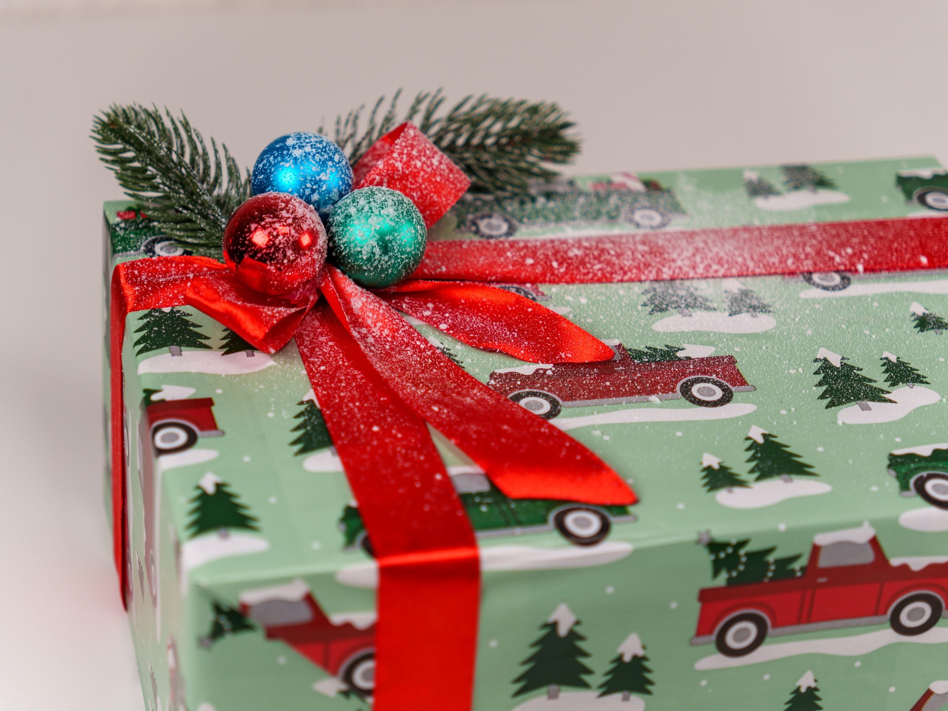 Unique holiday gift wrapped in festive paper with decorations and bow
