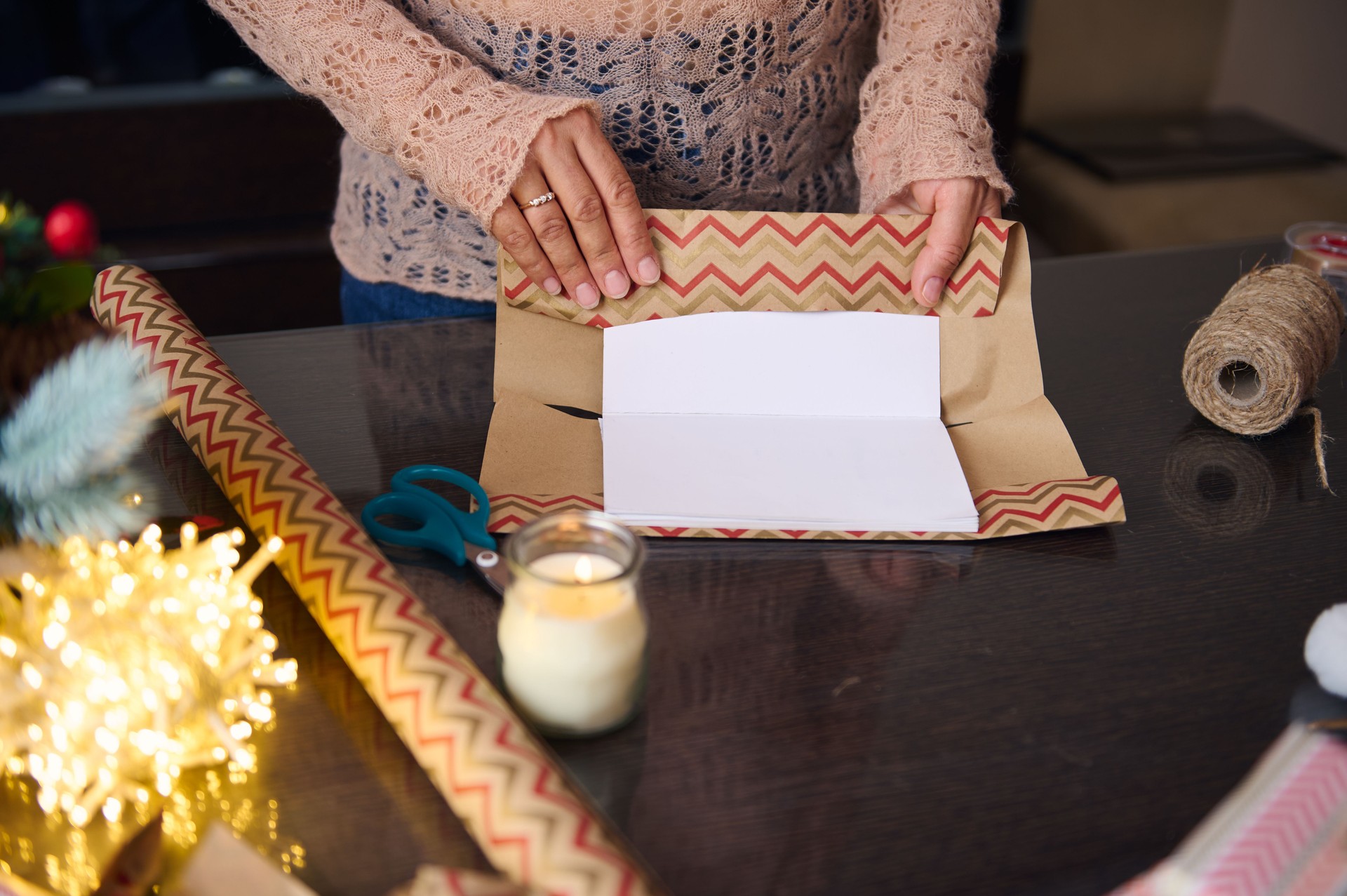 Hands Wrapping a Gift with Festive Paper on a Tabletop